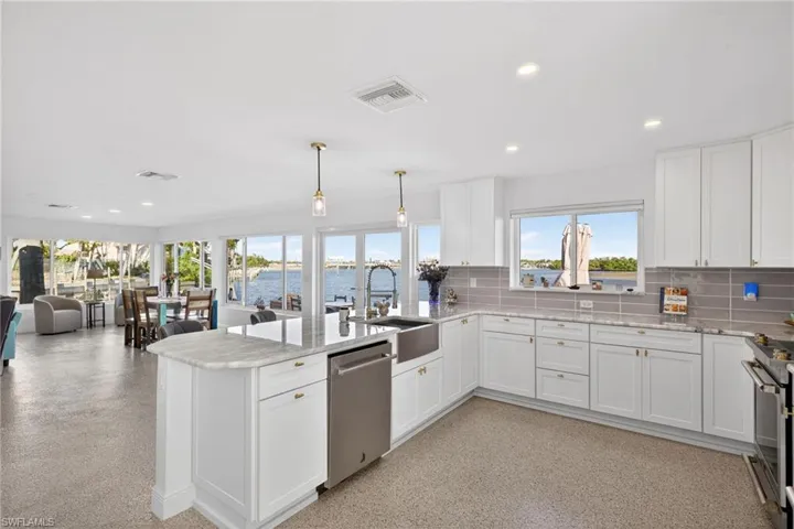 Kitchen featuring open floor plan, white cabinets, appliances with stainless steel finishes, recessed lighting, and light stone counters