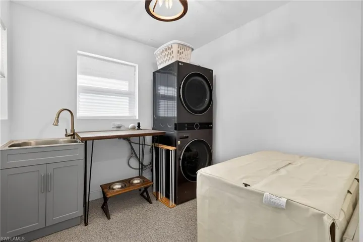 Laundry area featuring stacked washer / drying machine and dark aggregate flooring