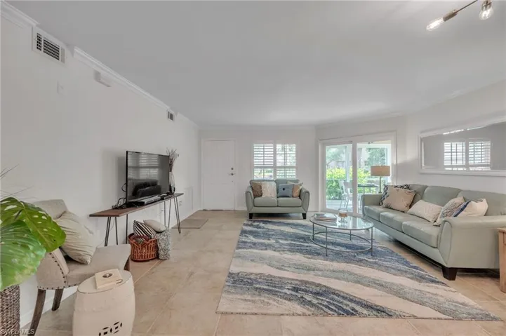 Living area featuring ornamental molding and light tile patterned flooring