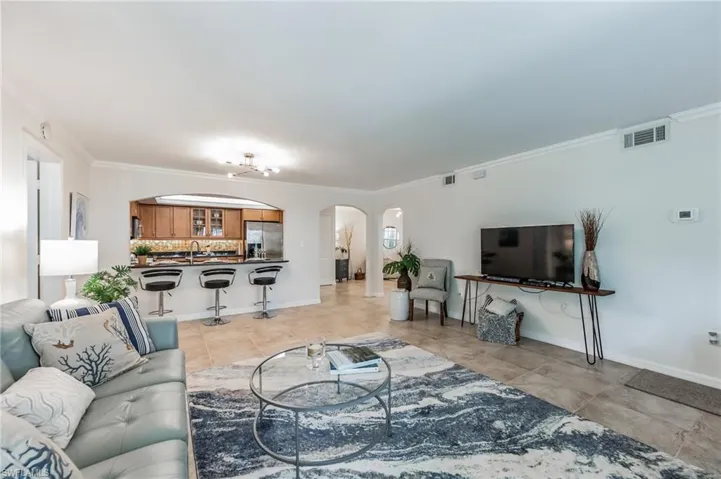 Living area with arched walkways, ornamental molding, and light tile patterned flooring