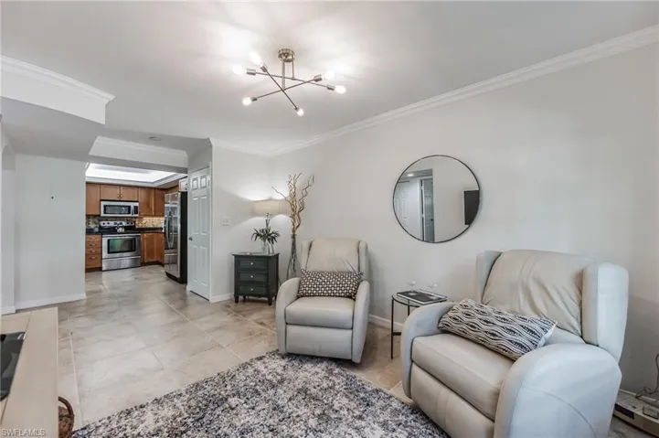 Sitting room with ornamental molding, a chandelier, and light tile patterned flooring