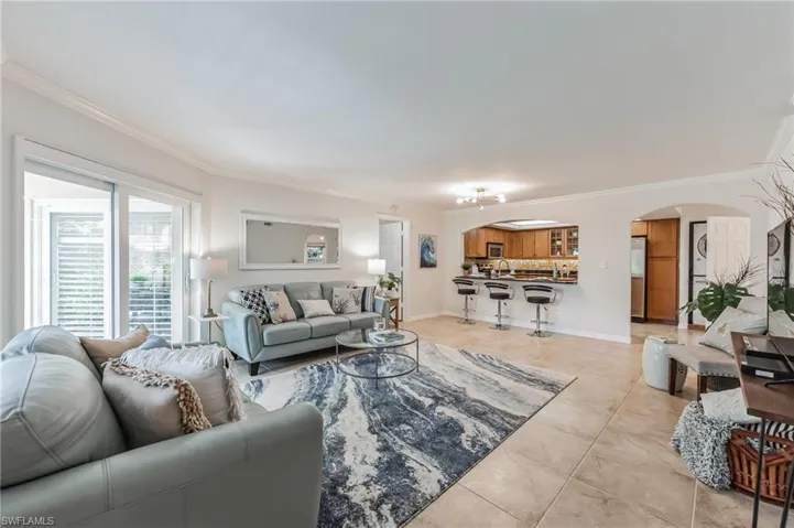 Living area with arched walkways, ornamental molding, and light tile patterned floors