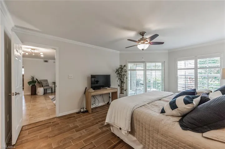 Bedroom featuring wood finish floors, crown molding, and ceiling fan