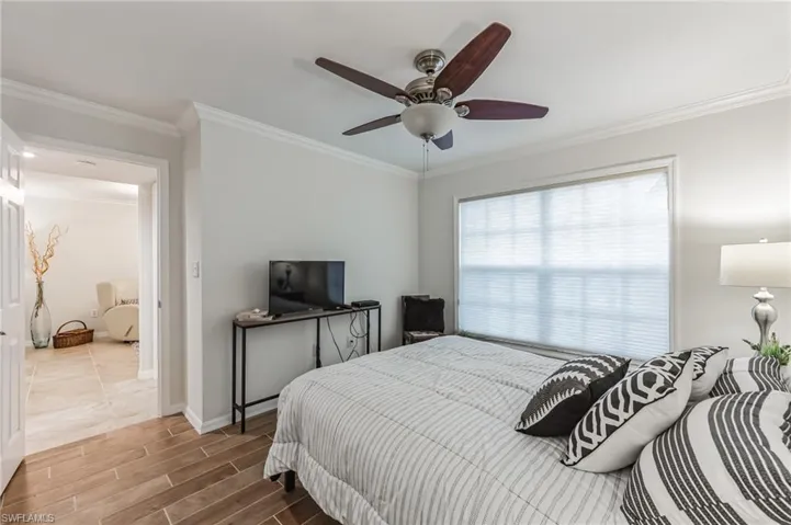 Bedroom with wood tiled floors, ornamental molding, and a ceiling fan