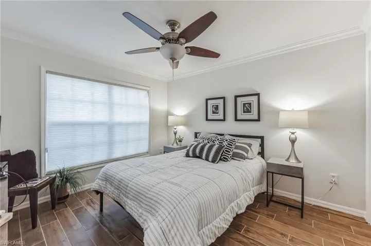 Bedroom featuring wood tiled floors, ornamental molding, and a ceiling fan