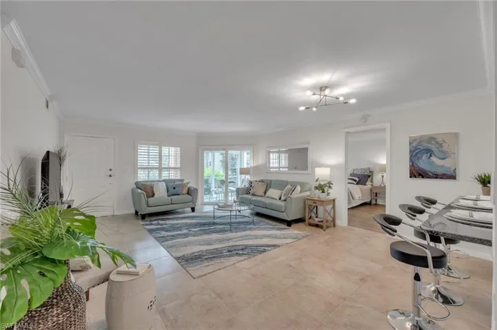 Living room featuring crown molding, a chandelier, and light tile patterned floors