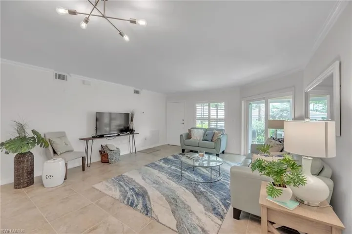 Living area featuring ornamental molding and a chandelier