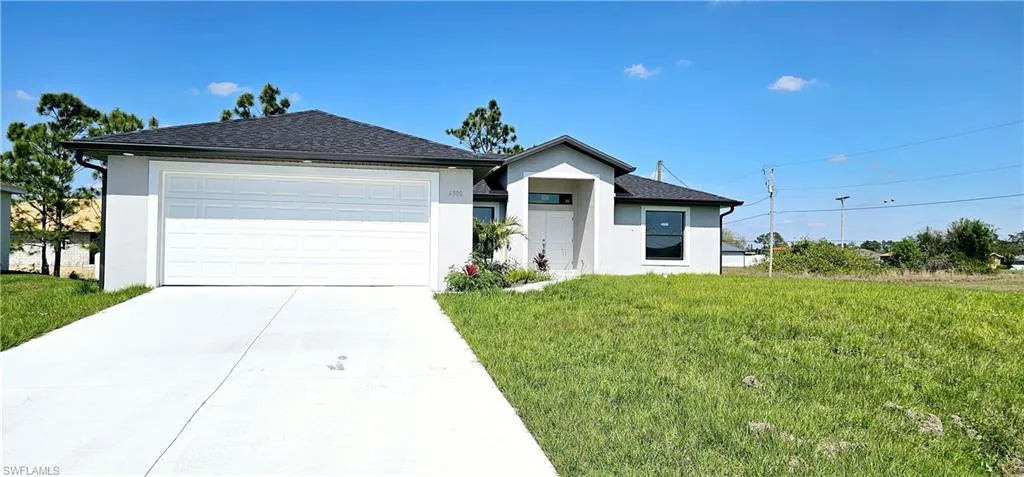 Ranch-style home featuring a garage, driveway, a front lawn, and stucco siding