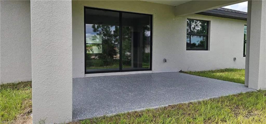 Entrance to property with stucco siding and a patio area