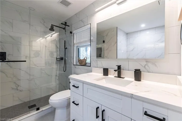 Bathroom featuring vanity, a shower stall, and tile walls