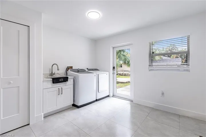 Washroom featuring cabinet space, washer and dryer, and light tile patterned floors