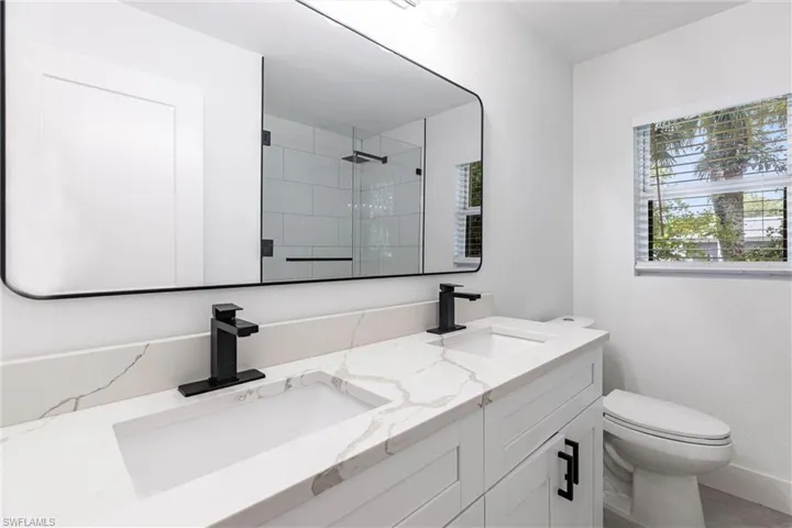 Bathroom with double vanity and tiled shower