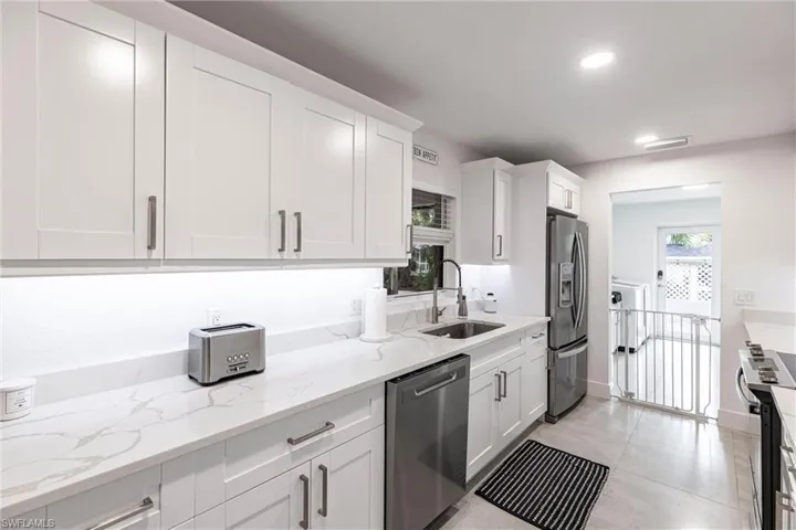 Kitchen featuring appliances with stainless steel finishes, white cabinets, light stone countertops, and recessed lighting