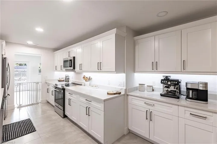 Kitchen with appliances with stainless steel finishes, white cabinetry, light countertops, light tile patterned flooring, and recessed lighting