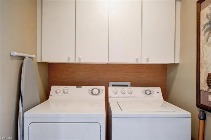 Clothes washing area featuring cabinets and separate washer and dryer
