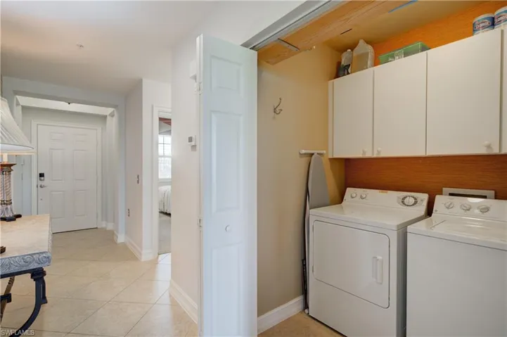 Laundry area featuring washer and clothes dryer, light tile patterned floors, and cabinets