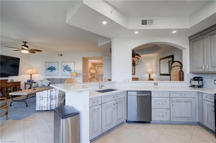 Kitchen with sink, stainless steel dishwasher, kitchen peninsula, gray cabinets, and light tile patterned floors