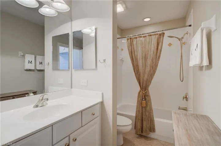 Full bathroom with tile patterned floors, vanity, shower / bath combo, and toilet