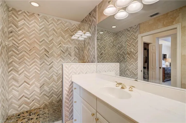 Bathroom with a shower, vanity, and tile walls