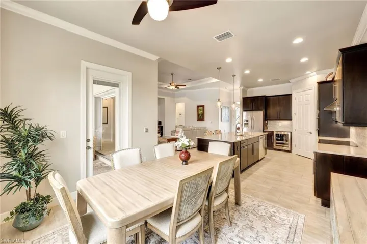 Dining space featuring wine cooler, sink, ornamental molding, and ceiling fan