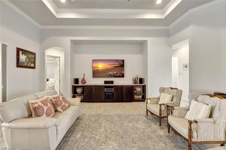 Living room with ornamental molding, a raised ceiling, and light hardwood / wood-style flooring
