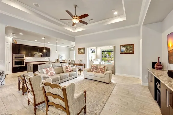 Living room featuring ornamental molding, a raised ceiling, and ceiling fan