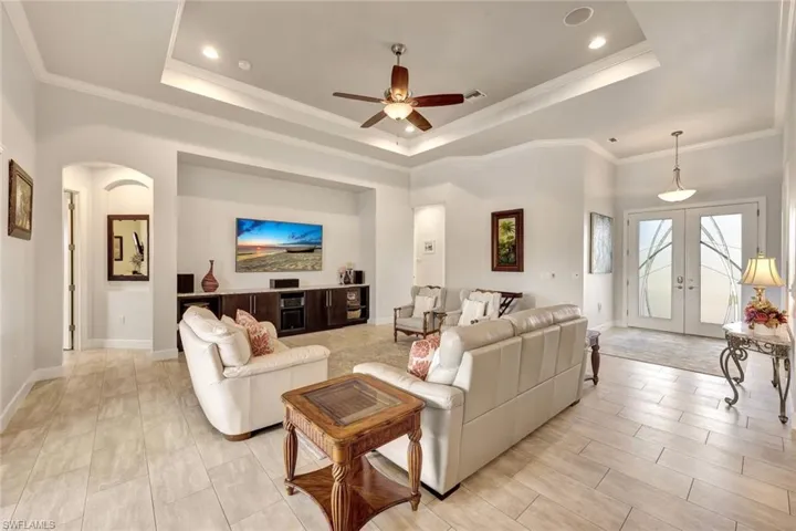 Living room with a raised ceiling, crown molding, and french doors