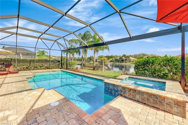 View of swimming pool featuring an in ground hot tub, a water view, a lanai, and a patio