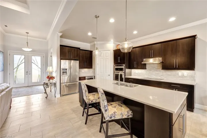 Kitchen featuring sink, dark brown cabinets, stainless steel appliances, decorative light fixtures, and french doors