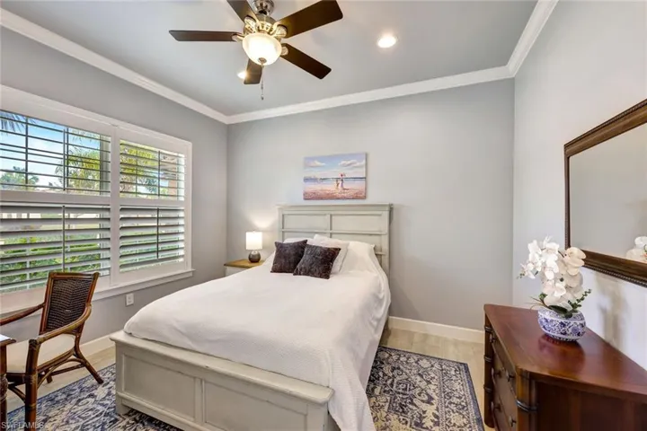 Bedroom with multiple windows, wood-type flooring, ornamental molding, and ceiling fan