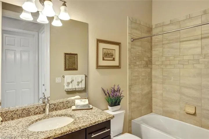 Full bathroom featuring vanity, toilet, tiled shower / bath combo, and a notable chandelier