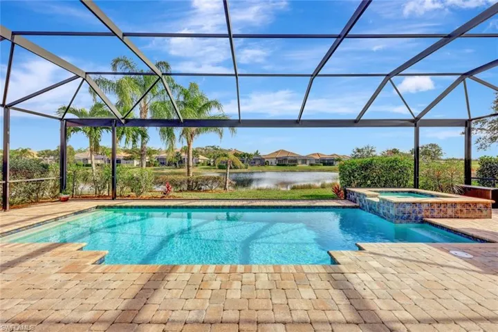 View of pool featuring a lanai, an in ground hot tub, a patio, and a water view