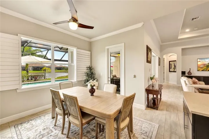 Dining area featuring a tray ceiling, crown molding, ceiling fan, and light wood-type flooring