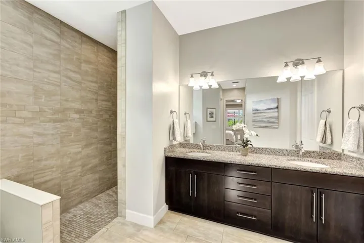 Bathroom with tiled shower, vanity, and tile patterned flooring