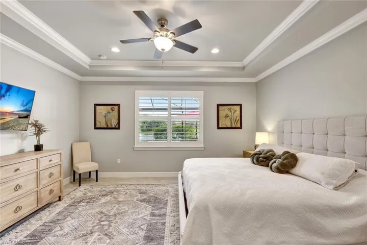 Bedroom featuring a raised ceiling, crown molding, and ceiling fan