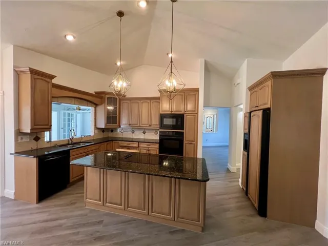 Kitchen featuring GRANITE TOPS, sink, hanging light fixtures, tasteful backsplash, a kitchen island, and black appliances