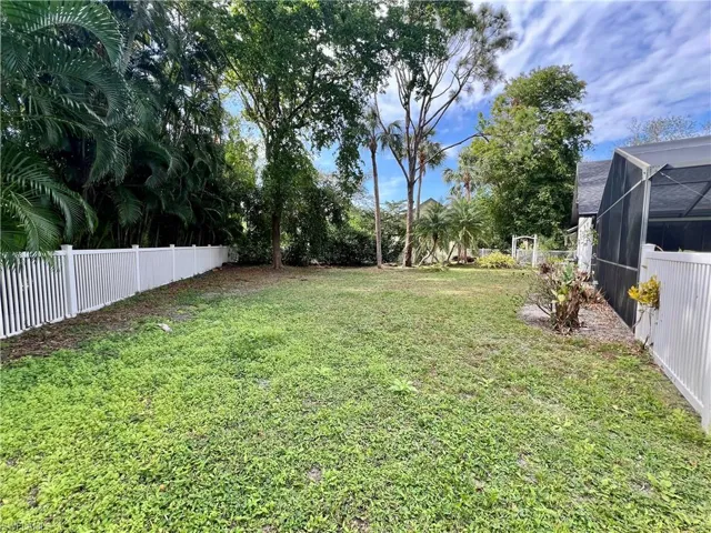 View of yard featuring a lanai and white PVC fencing.