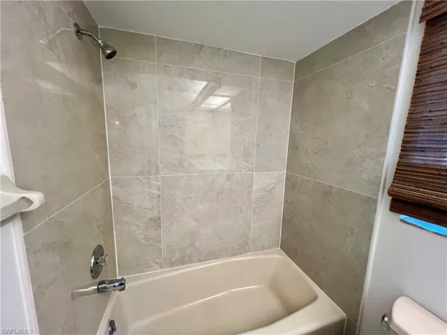 Bathroom with tiled shower / bath combo and toilet