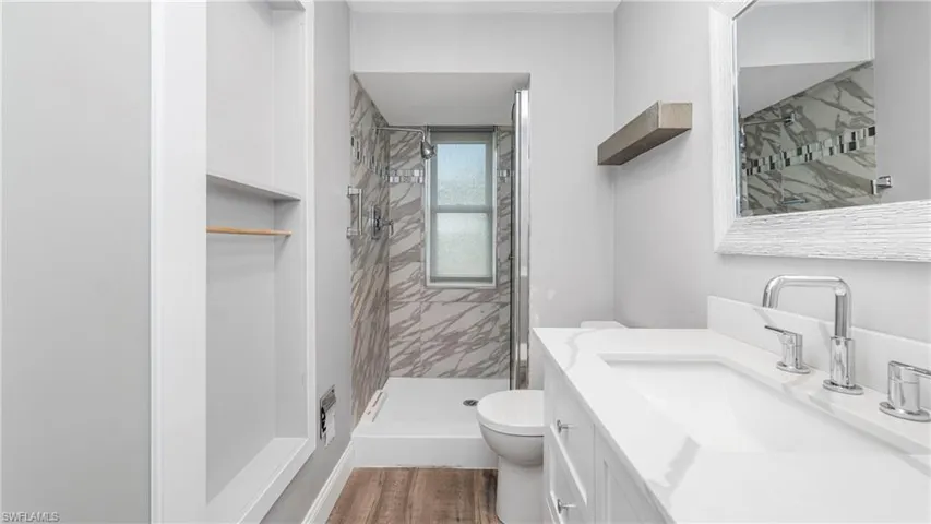 Full bathroom with vanity, a shower stall, and dark wood-type flooring