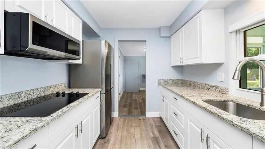 Kitchen with plenty of natural light, stainless steel microwave, and light stone countertops