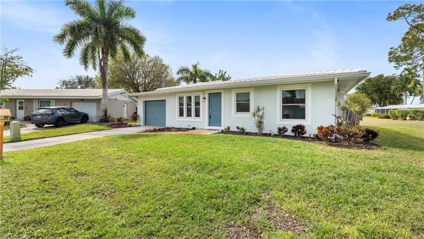 Single story home with an attached garage, a front yard, driveway, and stucco siding