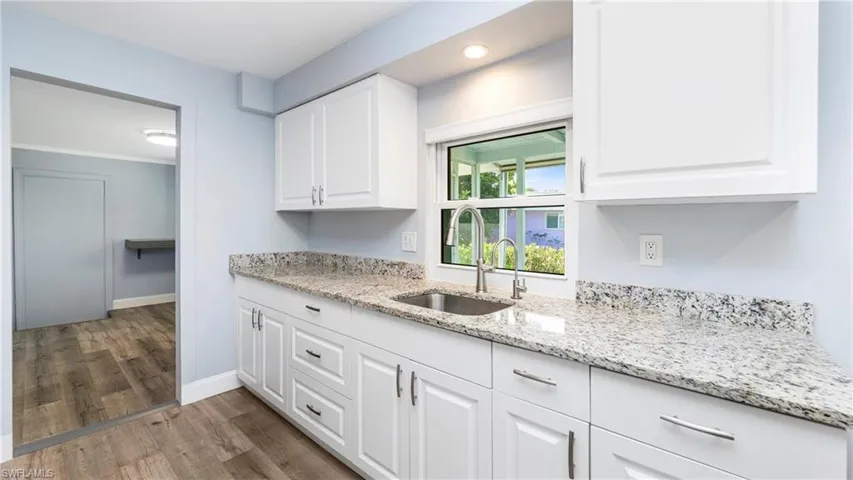 Kitchen featuring light stone counters, white cabinets, light wood-style flooring, and recessed lighting