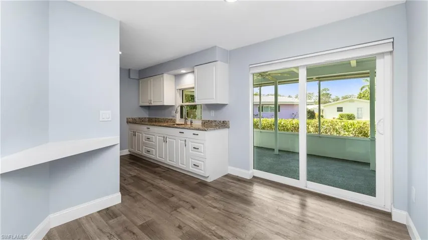 Kitchen featuring white cabinets, dark stone countertops, dark wood-type flooring, and recessed lighting