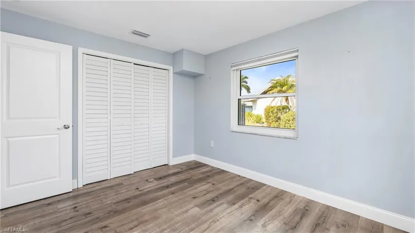 Unfurnished bedroom featuring dark wood-style flooring and a closet