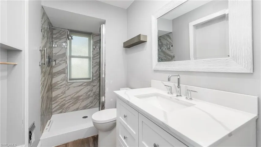 Full bathroom featuring vanity, a stall shower, and dark wood finished floors