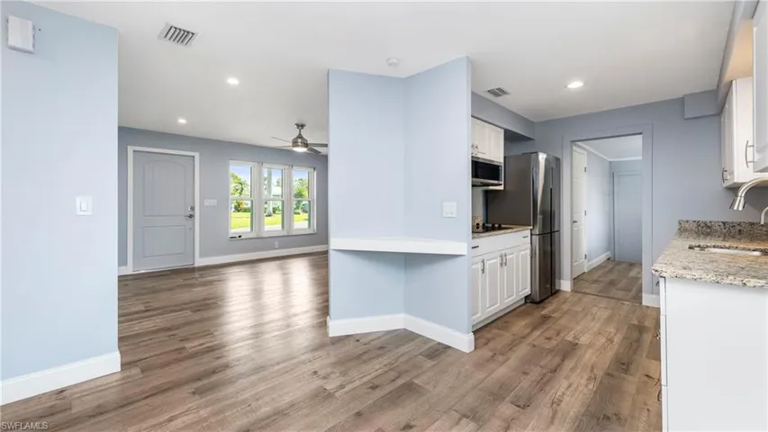 Kitchen with white cabinets, light wood-style floors, light stone counters, open floor plan, and recessed lighting