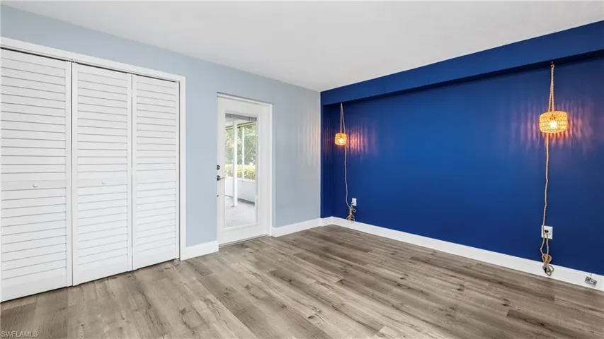 Unfurnished bedroom with wood finished floors, access to outside, and a closet