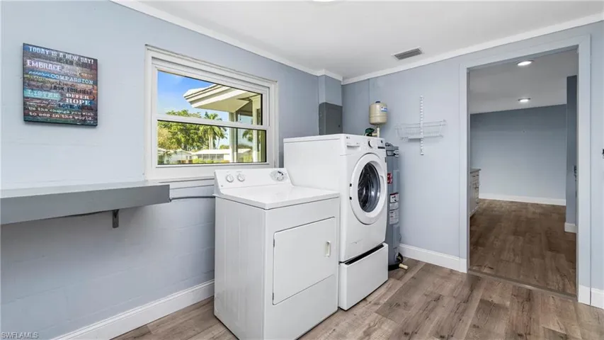 Laundry room featuring light wood-style floors, separate washer and dryer, electric water heater, and ornamental molding