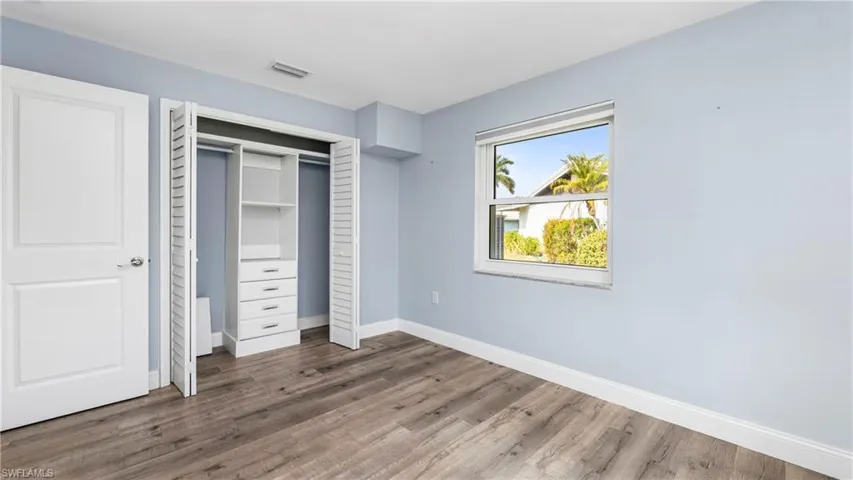 Unfurnished bedroom with a closet and dark wood-style floors