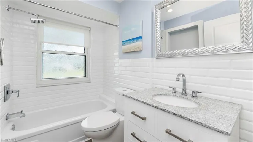Bathroom with tile walls, vanity, and bathing tub / shower combination